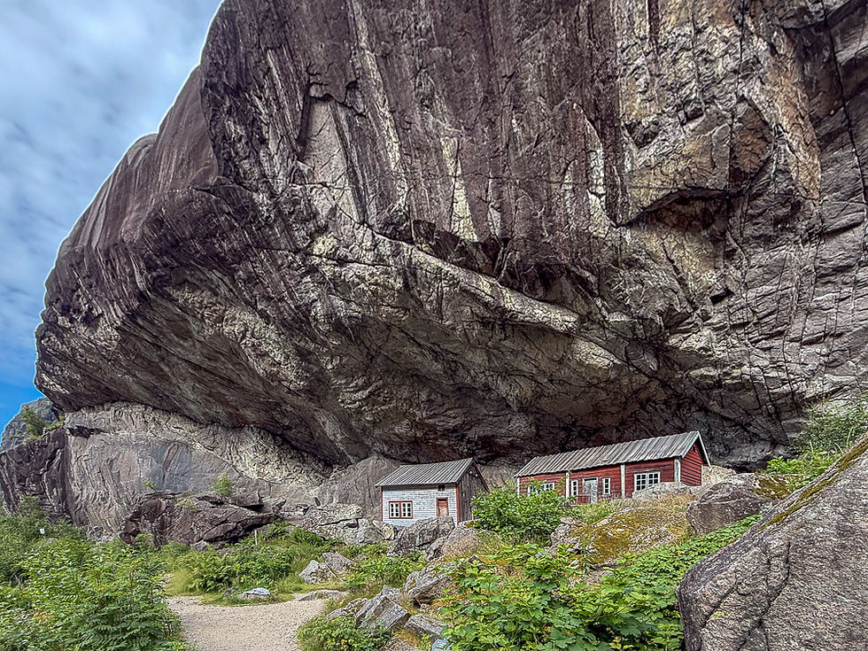 To gamle trehus under et stort bergutspring kalt Helleren i Jøssingfjord