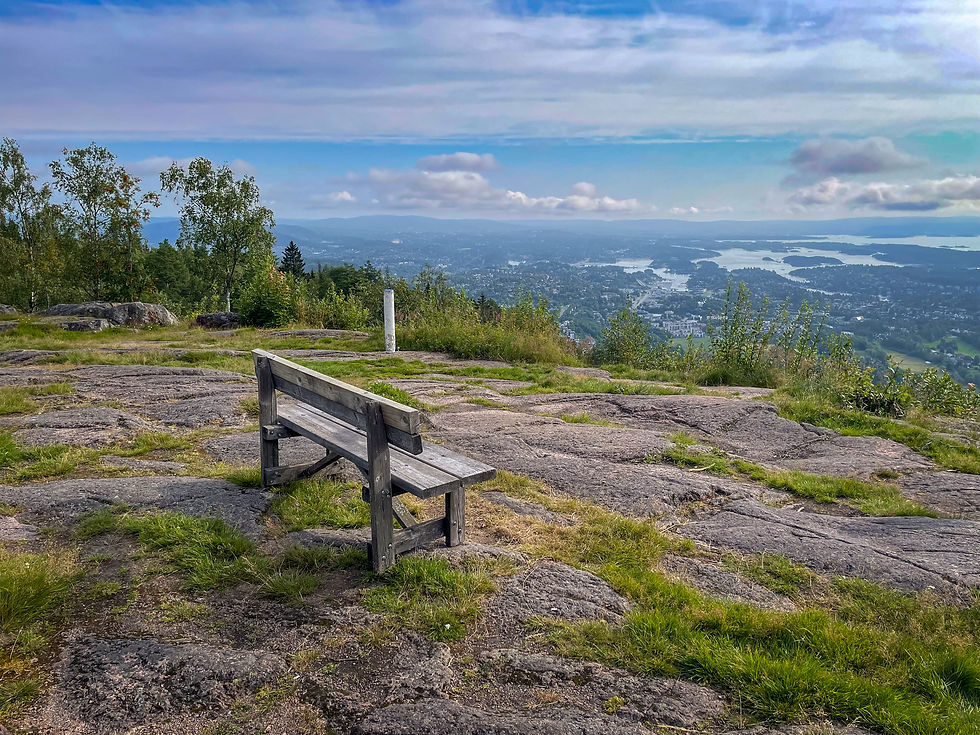 En benk på en fjelltopp med utsikt over fjord med øyer