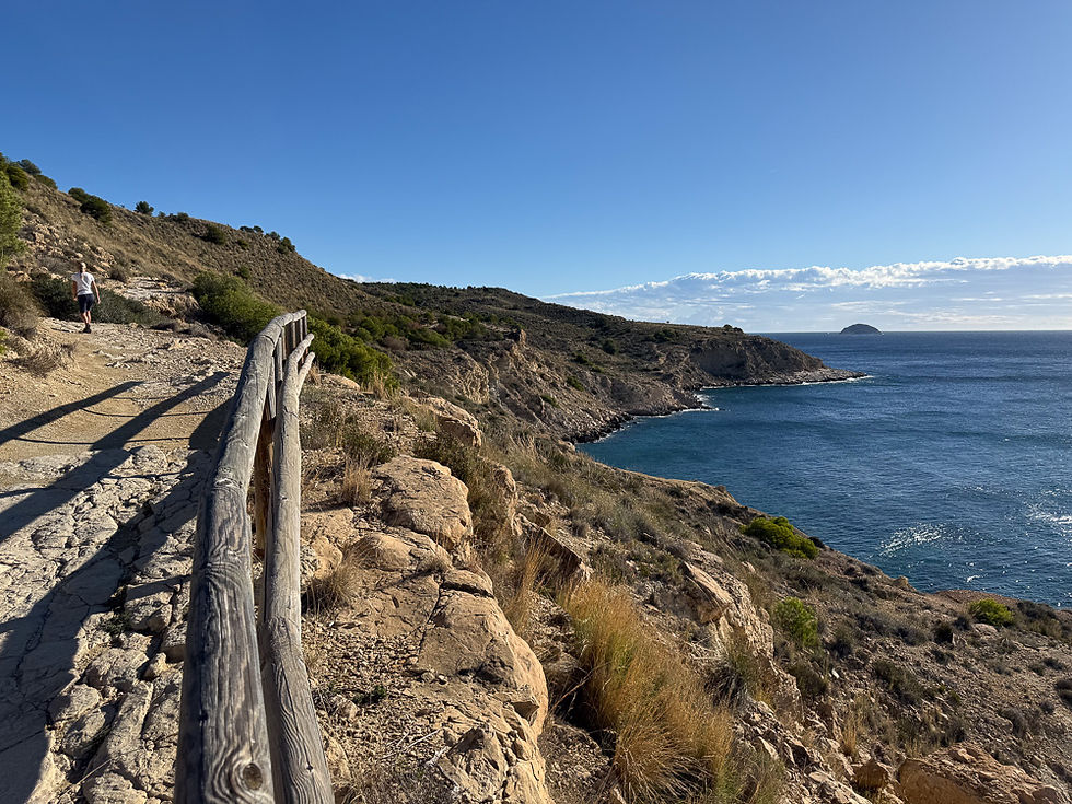 Kvinne går på sti på toppen av klippe beskyttet med gjerde ved Villajoyosa på Costa Blanca