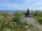 Kvinne på benk ved havet med blomster foran ved Sveriges sydligste punkt Smygehuk i Skåne i Sverige