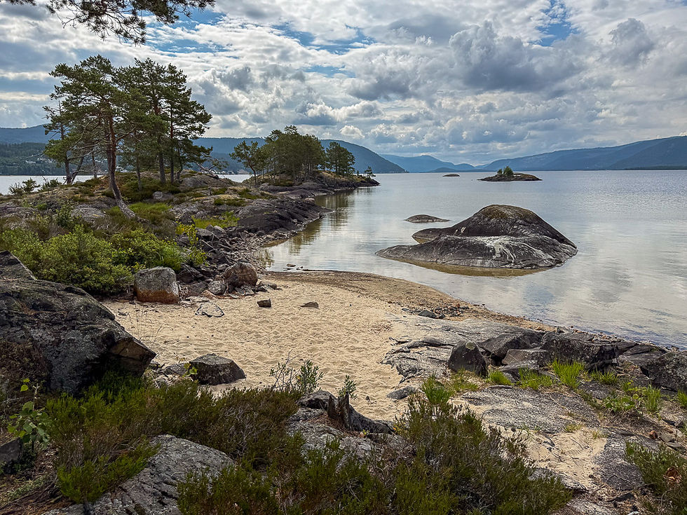 Liten sandstrand med holmer og skjær ved Paradisbukta i Fjoneferja i Nisser