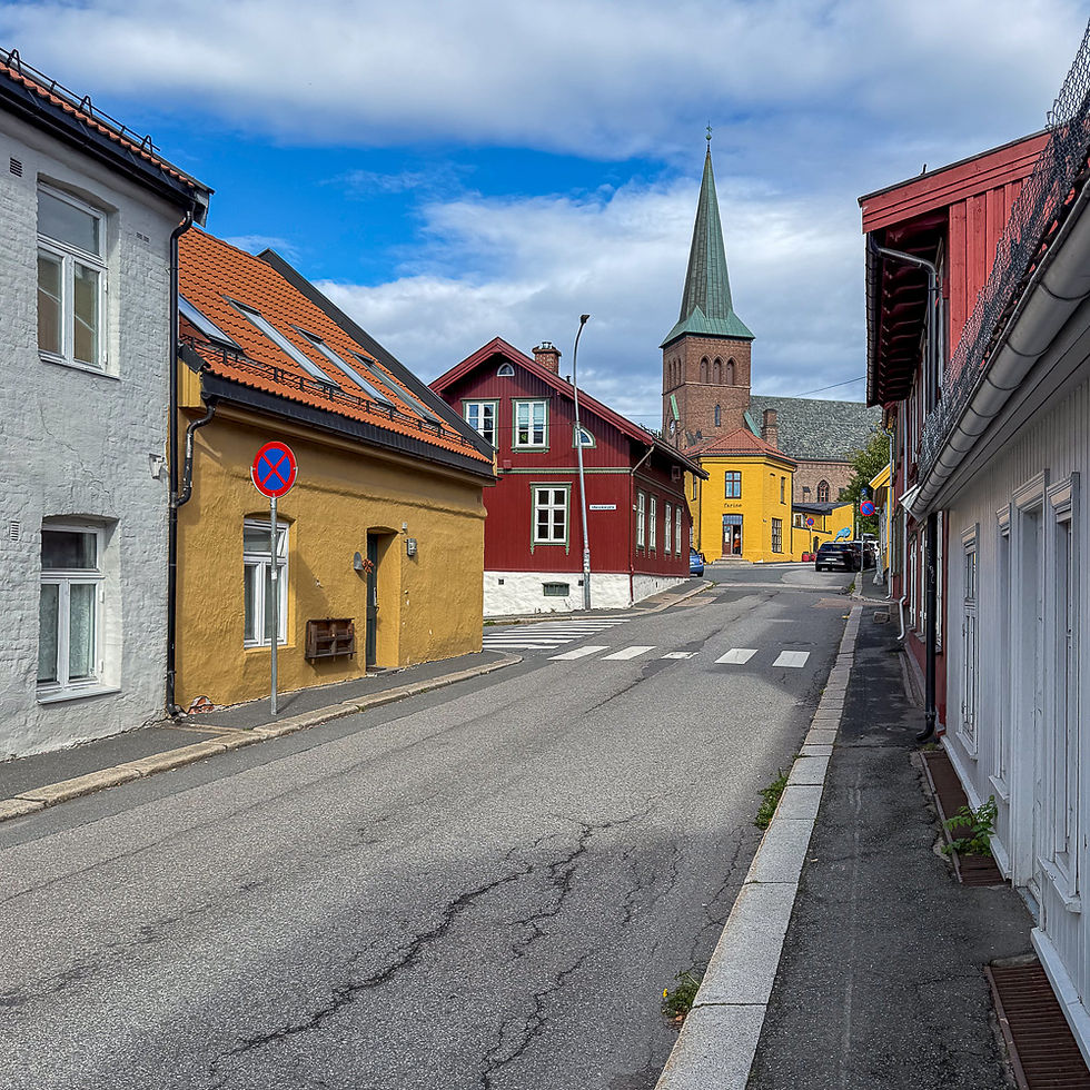 Bygate med gammel bebyggelse og kirke med grønt spir i Kampen i Oslo