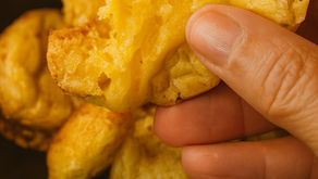 uma mão segurando um pão de queijo cortado.