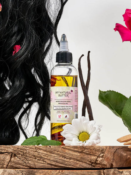 Moisturizing Hair Growth Oil bottle shown with black hair, vanilla bean, and flowers.