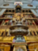 L'intérieur de l'église décoré d'une secte de secte qui comprend des statues et des peintures religieuses. Base de tasse en argent au premier plan. Verre de couleur vive au-dessus.