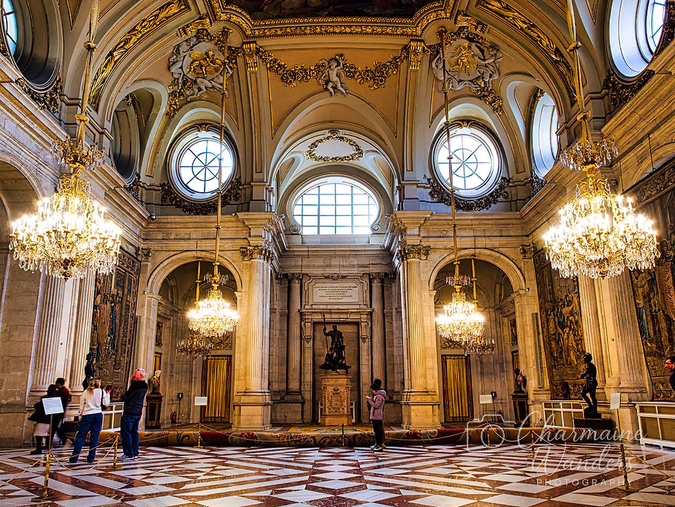 Ornate hall with grand chandeliers, marble floor, and intricate gold details. Visitors admire the decor and statues. Elegant, historic atmosphere.