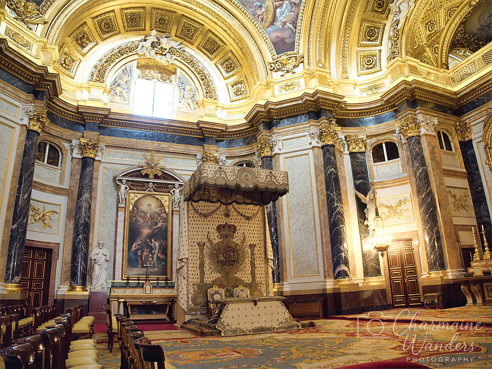 Ornate interior with golden ceiling, large painting, and altar. Luxurious drapery, marble columns, and chairs line the room. Elegant decor.