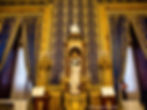 Salle décorative avec murs en relief bleu et doré, chandelier doré, axe d'une statue détaillée et rideaux en dentelle. Décor élégant et historique.