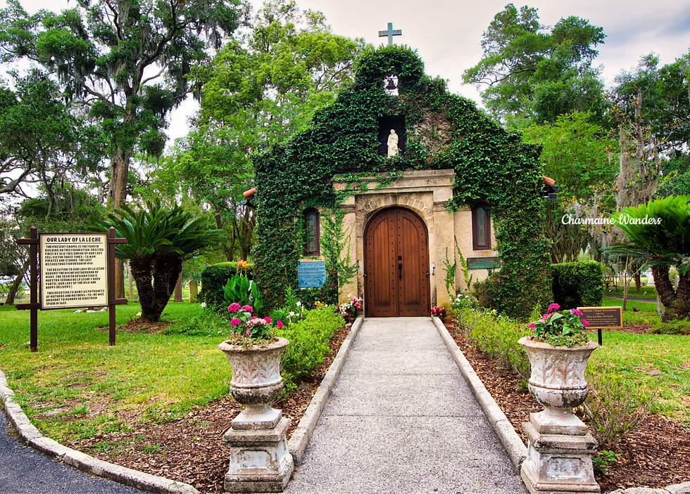 Ivy-covered chapel with a wooden door, flanked by planters with pink flowers. Sign reads "Our Lady of La Leche." Lush green surroundings. Mission Nombre de Dios, St. Augustine, Floria