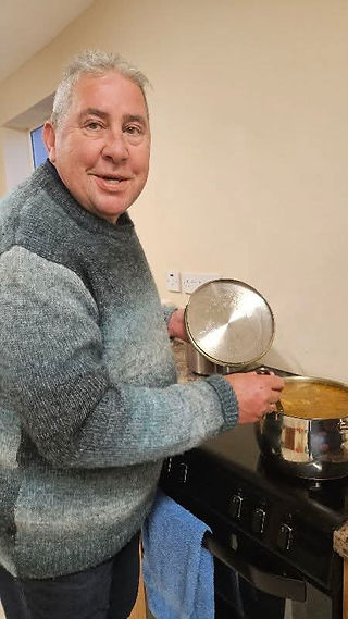 Man smiling, holding a pan in kitchen