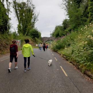 People walking on paved path, small dog