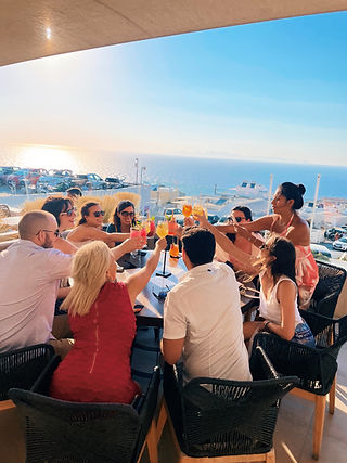 Travelrs toast colorful drinks along the coast of Greece.
