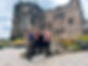 Solo travelers smiling infront of a historic stone castle in Scotland