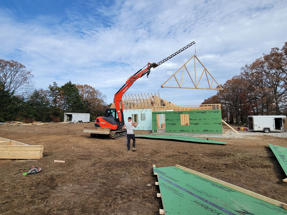 Construction site with crane lifting wooden truss.
