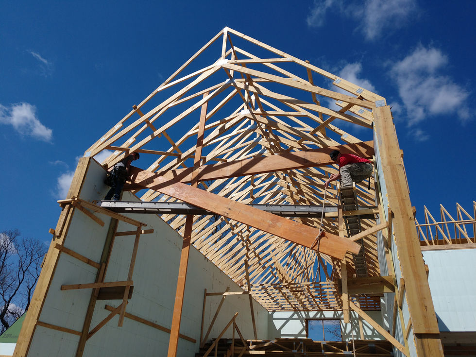 Wooden house frame under construction against blue sky.