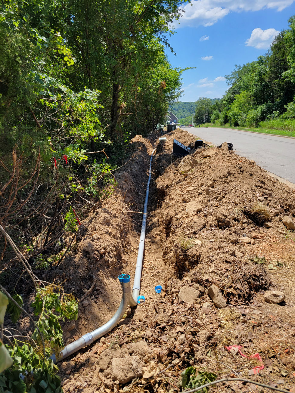 Trench with pipe installation beside a road.