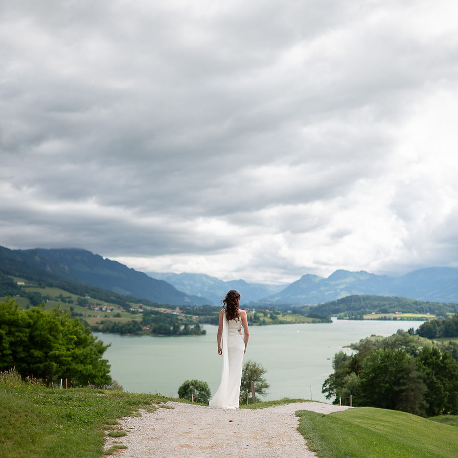 Mariée de dos face au lac et aux montagnes lors d’un mariage intime en Suisse