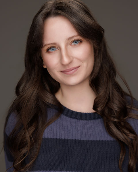 Young female actor theatrical headshot smiling against gradient gray background