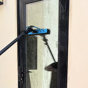 : Professional window squeegee wiping a glass pane clean to leave a streak-free shine.
