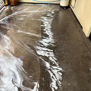 High-pressure water and foam lifting dark organic growth off dirty porch steps.