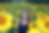 Picture of Kelly Fagan in a field of sunflowers, smiling, wearing a navy dress and a gold heart locket