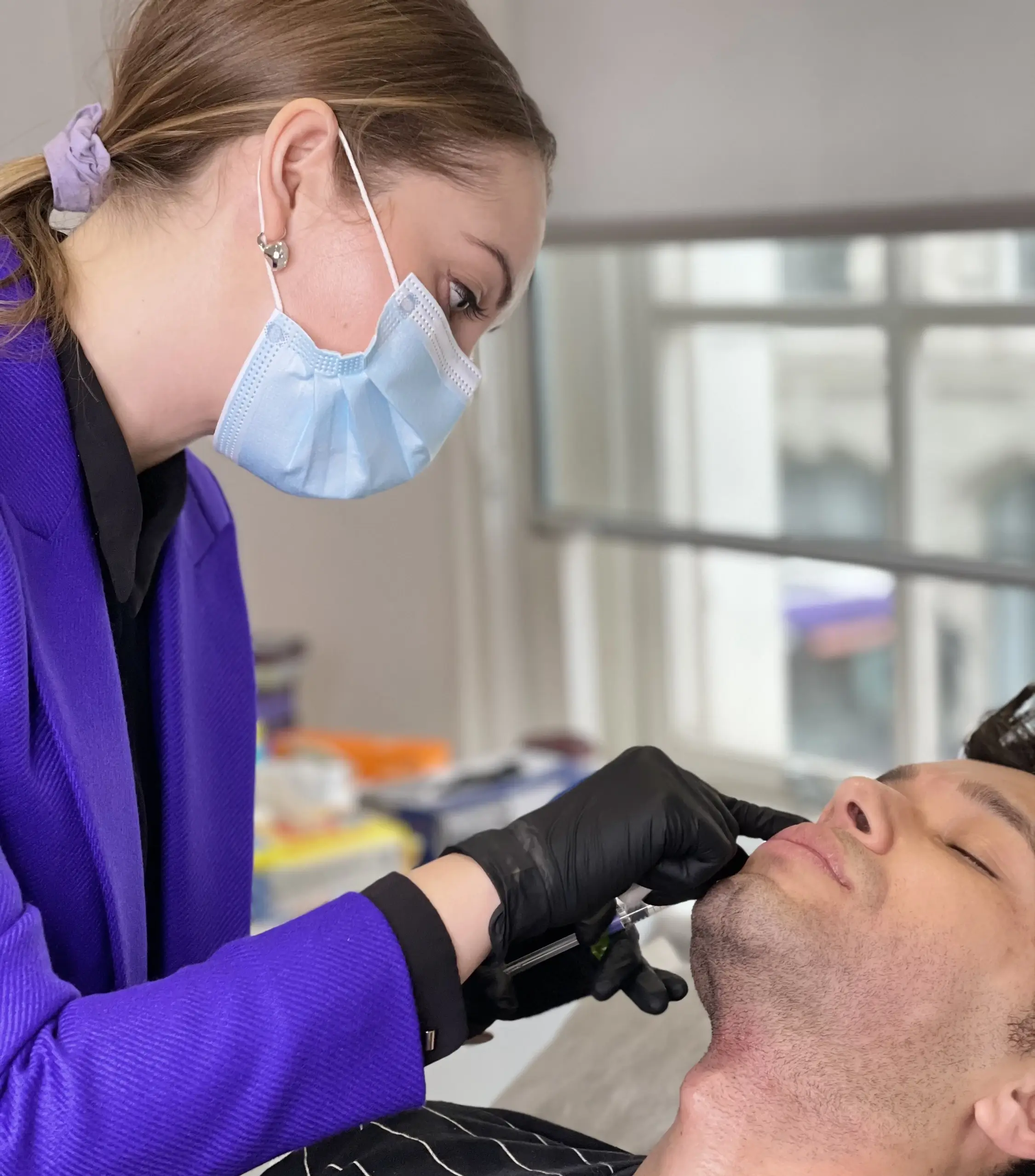 doctor performs facial aesthetic injection on a young handsome male patient