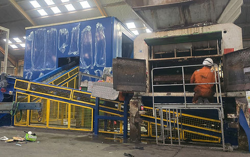 A landscape image of the conveyor system with a man in orange protective clothing and a white hard hat working on the system