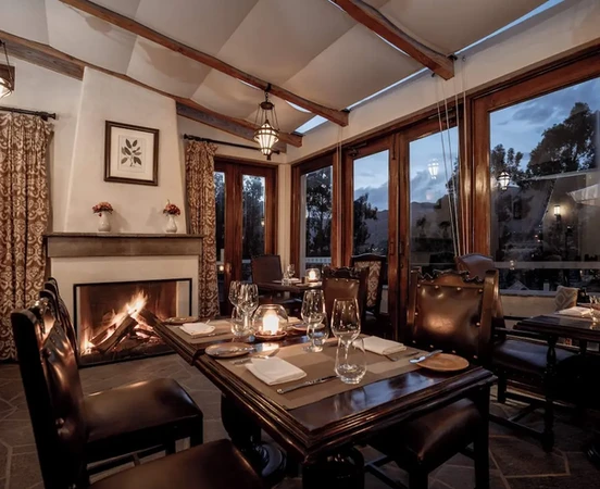 Intérieur chaleureux du restaurant Curiña avec cheminée et vue sur les Andes à Las Casitas, A Belmond Hotel
