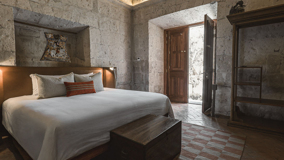 Meilleur hôtel de luxe à Arequipa : La Suite Deluxe du Palacio Guaqui s'ouvrant sur un patio lumineux, avec lit grand confort et coffre en bois, une exclusivité Graine de Voyageur.
