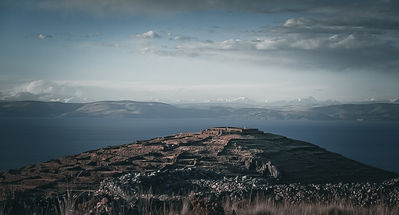 Vue panoramique de l’île d’Amantani sur le lac Titicaca, avec ses terrasses agricoles et son horizon montagneux, symbole de la culture andine.