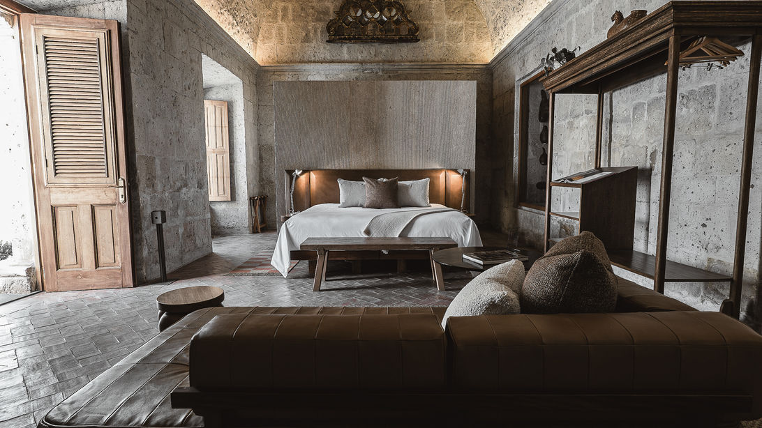 Hôtel de prestige Palacio Guaqui à Arequipa : Intérieur lumineux de la Suite Junior avec canapé en cuir, lit grand confort et porte en bois ouverte, sélectionné par l'agence Graine de Voyageur.