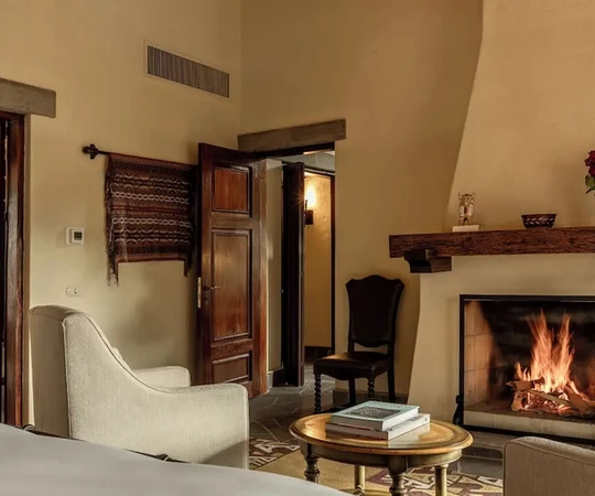 Coin salon chaleureux avec cheminée traditionnelle en pierre dans une Casita Garden View, Las Casitas, Pérou