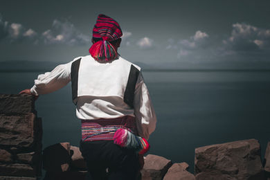 Photo d’un homme de l’île de Taquile, portant un pantalon noir, une chemise blanche et un bonnet tricoté coloré, symbole de la tradition vestimentaire et culturelle andine du Pérou.