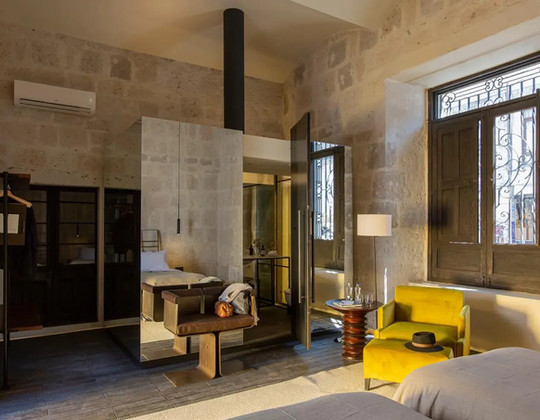 Suite Aposento design Cirqa Arequipa avec voûte brique et fauteuil jaune.