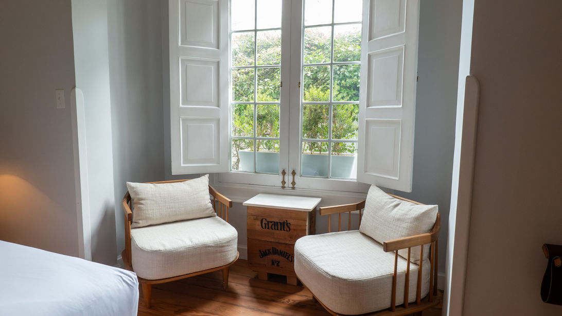 Coin salon intime avec fauteuils et fenêtre donnant sur le jardin de la Villa Barranco, boutique hôtel exclusif à Lima.