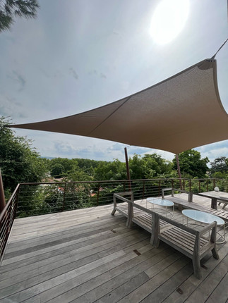 Voile d'ombrage suspendu au dessus d'une terrasse avec un salon de jardin