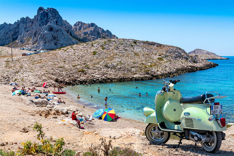 Les Goodes Marseille, France, Grüne Vespa am felsigen Strand. Menschen schwimmen im türkisfarbenen Wasser, bunte Sonnenschirme am Ufer. Sonniger Tag, Berge im Hintergrund.