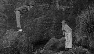 bride and groom standing on rocks leaning towards each other with lips puckered for a kiss