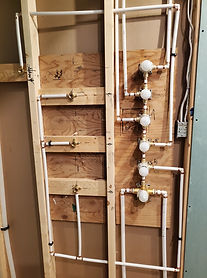 organized white water lines and valves inside of a wall being constructed