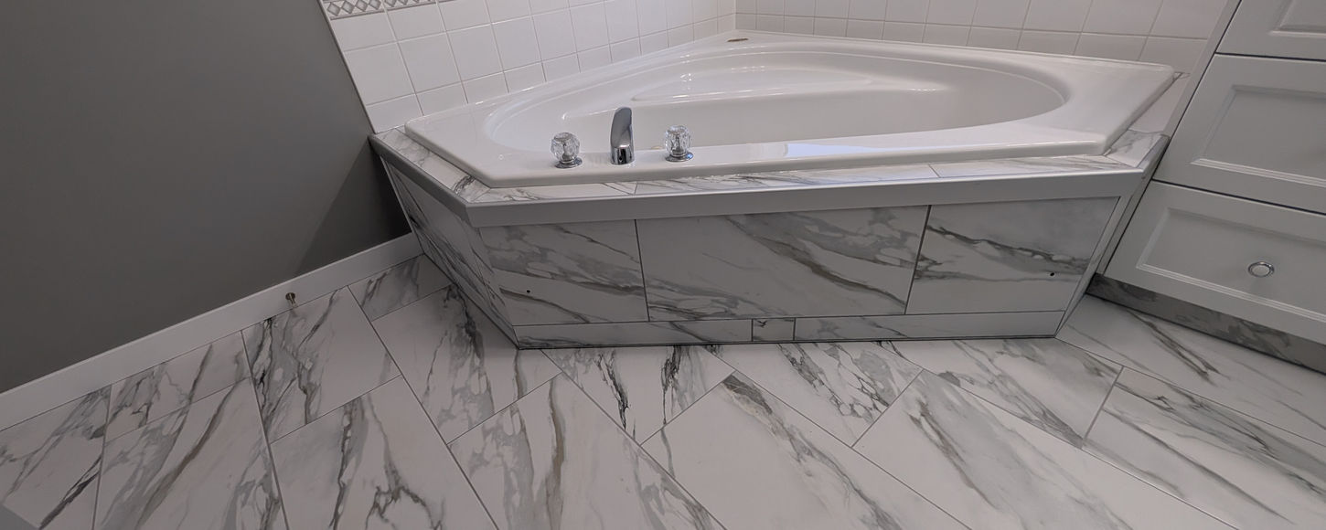 Corner jacuzzi tub tile installation in Regina with marble look tile by B-Flex Services.