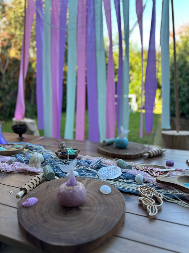 Outdoor messy party table setup with pastel ribbons and sensory play items