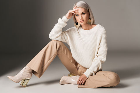 attractive fashionable woman posing in white trendy sweater, beige pants and autumn heels,