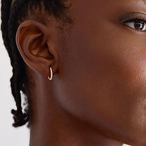 Black model with canerows wearing small twist huggie hoop earrings - close shot