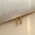 Small green ankh pave charm huggies on beige styled background