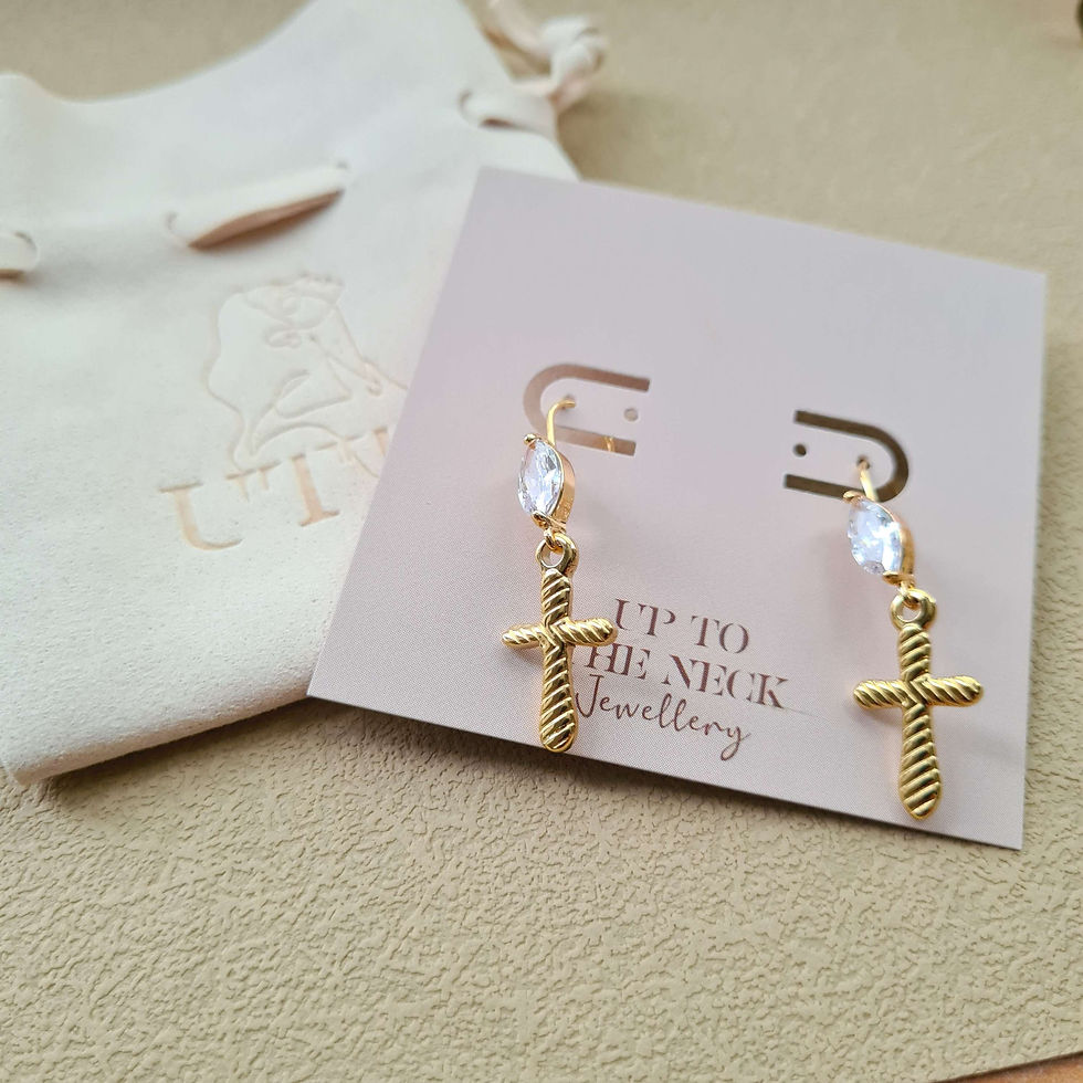 Thumbnail: Gold cross drop earrings with zirconia marquise stone on packaging card and cream brand jewellery bag