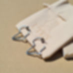Silver Africa hoop earrings laying next to branded jewellery bag