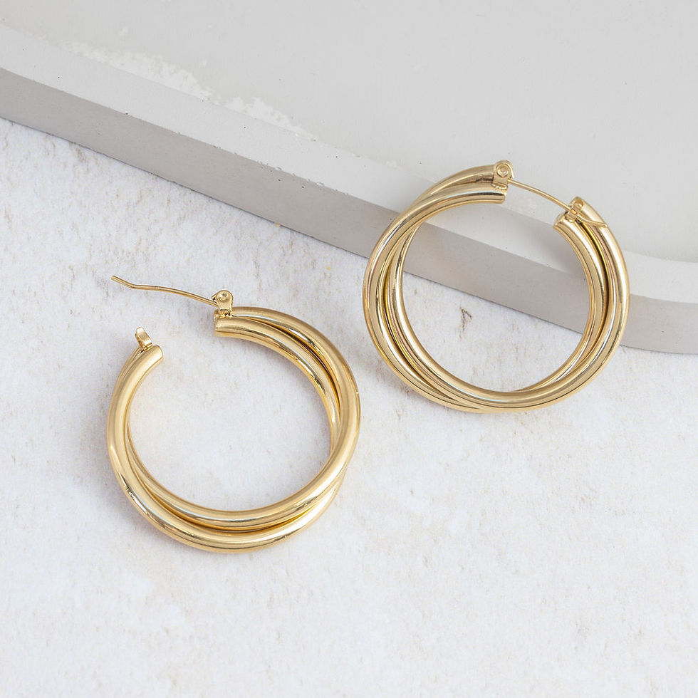 Thumbnail: Dual entwined gold hoop earrings laying against jewellry dish