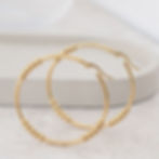 Thumbnail: Gold hoops standing on grey concrete tray on table