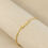 Thumbnail: Gold custom personalised name bracelet saying Iman on beige textured surface
