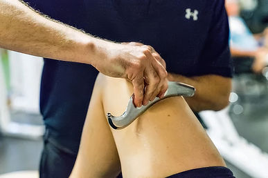 Physical therapist uses a specialized tool on a patient's leg to enhance the benefits of manual therapy techniques